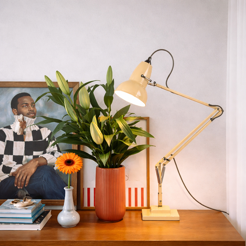 Gelbe verstellbare Tischlampe neben Pflanzen