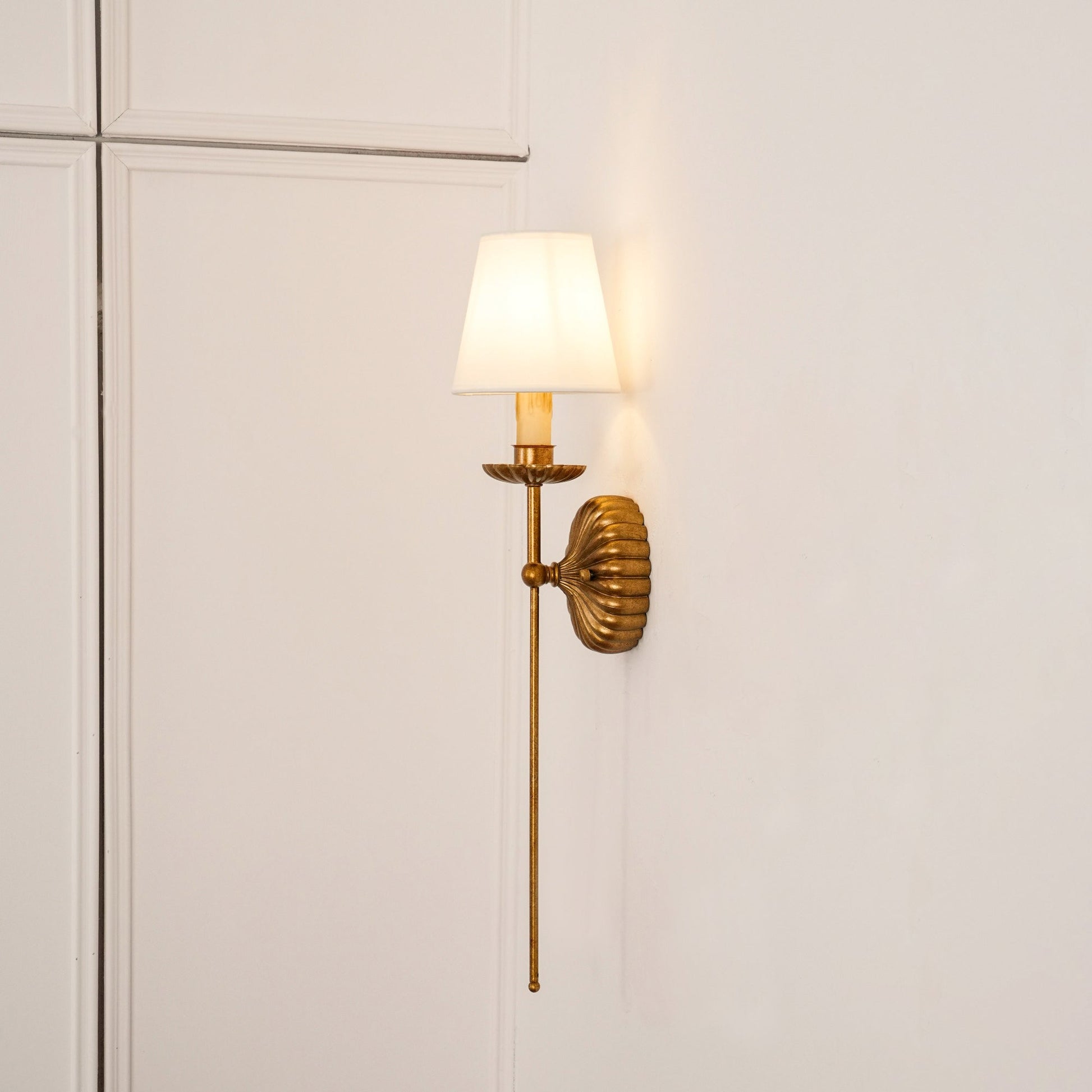 Catina Wandleuchte in Antikgold an einer Wand